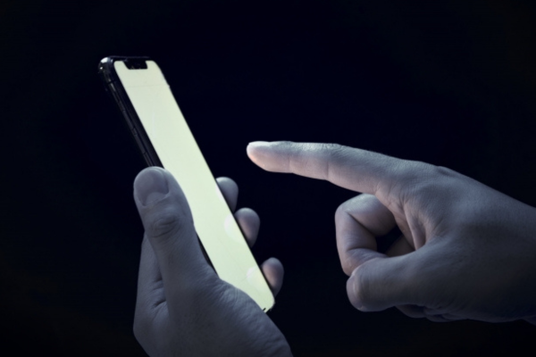 暗いところで携帯電話を手に持つ画像